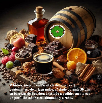 A styled still life of a wooden barrel and a bottle of amber liquor, with a glass of black coffee in the foreground, surrounded by chocolate bars, citrus slices, berries, spices, and coffee beans on a dark rustic surface. Spanish text appears at the bottom describing the whiskey aging process.
